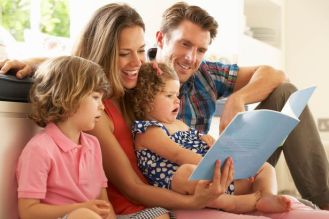 Parents-Sitting-With-Children-Reading-Story-Indoors